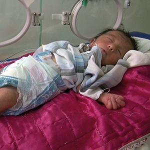 Auf der Neugeborenenstation der Kinderklinik in Falludscha, 2012. Dieses Mädchen kam mit einem Herzfehler und deformierten Armen und Beinen zur Welt. Eine Studie von 2010 stellte bei 14,7 % aller in Falludscha geborenen Kinder Missbildungen fest. 